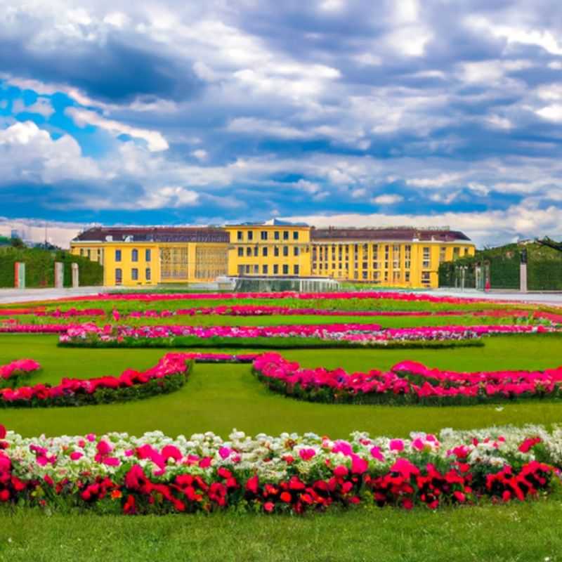 Four intrepid travelers marvel at the grandeur of Vienna's Hofburg Palace, a majestic winter wonderland adorned with snow-laden turrets and elegant facades, during their extended 3-week sojourn in the heart of Austria's captivating capital.