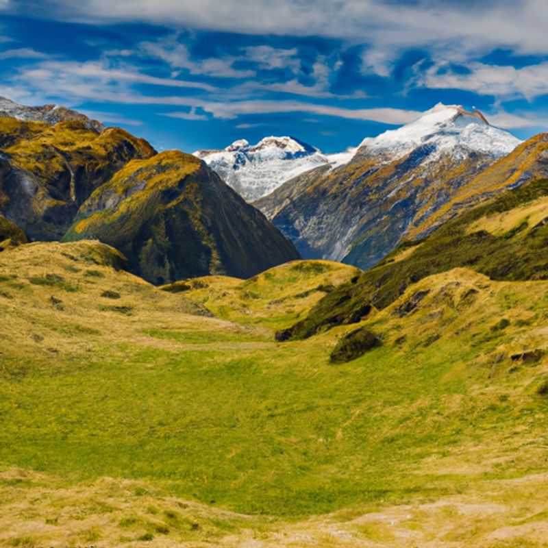 A solitary traveler stands atop Cascade Saddle, New Zealand, enveloped by the ethereal beauty of snow-capped mountains and a vast, untouched wilderness, embarking on a transformative 3-day winter journey of self-discovery and connection with nature's grandeur.